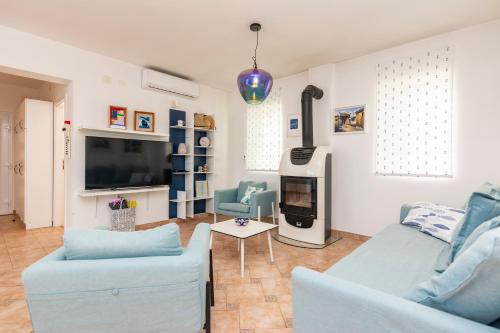a living room with two blue chairs and a tv at Holiday home with swimming pool - Dugi otok, Zman in Žman