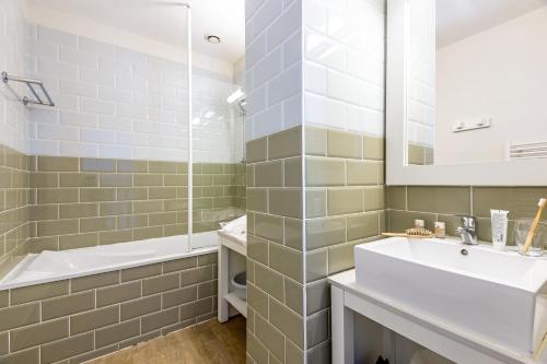 ein Badezimmer mit einem Waschbecken, einer Badewanne und einem Spiegel in der Unterkunft Résidence Pierre & Vacances Le Palais des Gouverneurs in Saint-Martin-de-Ré