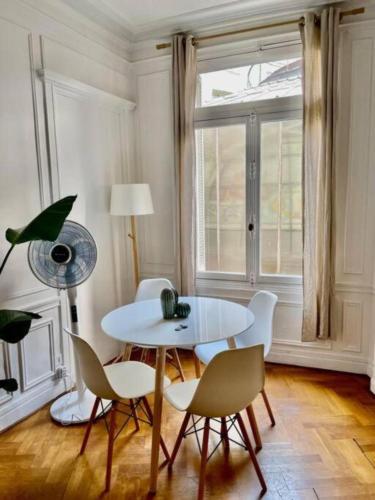 une table blanche et des chaises dans une pièce avec une fenêtre dans l'établissement A Luxurious Apartment with AC on Promenade des Anglais, à Nice