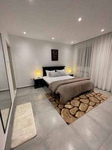 a bedroom with a large bed and a rug at Logement Chic, résidence azaléa - Alger in Draria