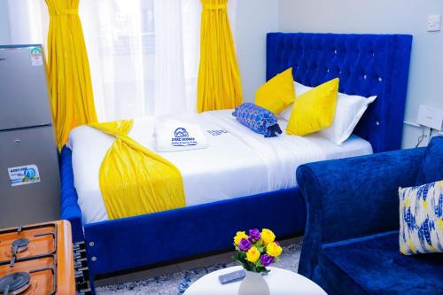 Una cama azul con cortinas amarillas y una silla azul en Enac Homes - Classy, Elegant Executive Studios - Kiambu Road, en Kiambu