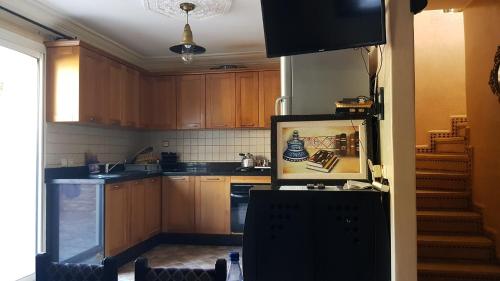 cocina con armarios de madera, TV y escaleras en Havre de paix pied dans l'eau en Agadir