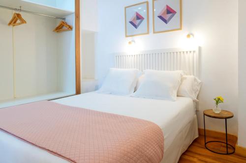 a bedroom with a white bed with a pink blanket at Casa de la Catedral in Granada