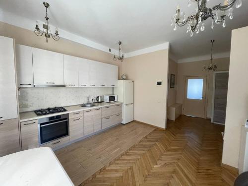 a kitchen with white cabinets and a wooden floor at Guest house, Jūrmala in Jūrmala