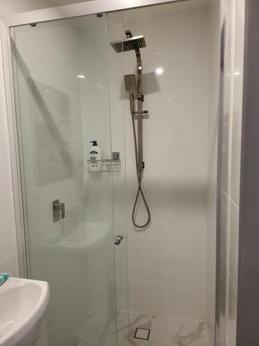 a shower with a glass door next to a sink at T&V Suites in Windsor
