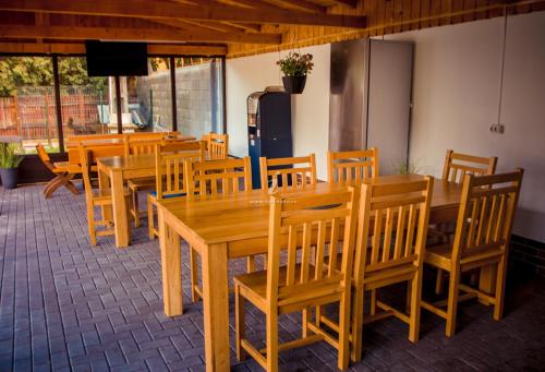 CăciulataにあるPensiunea Teodora Caciulataの木製のテーブルと椅子、冷蔵庫が備わるレストラン