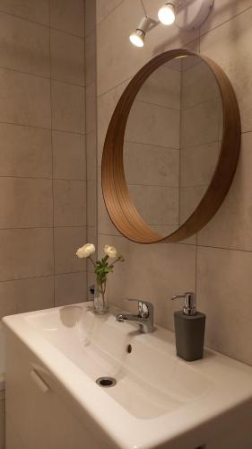 - un lavabo avec un vase de fleurs et un miroir dans l'établissement Eliza Apartman Veszprém, à Veszprém