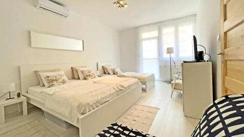 een witte slaapkamer met een bed en een bank bij Eliza Apartman Veszprém in Veszprém