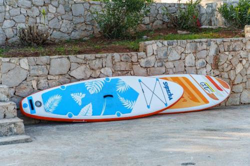 two surfboards sitting next to a stone wall at Holiday home with swimming pool - Dugi otok, Zman in Žman