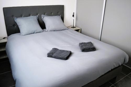 1 cama blanca grande con 2 toallas en La Mer Veille, maison neuve avec jardin, en Courseulles-sur-Mer
