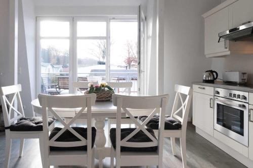 een keuken met een witte tafel en stoelen en een keuken met een raam bij Villa Marin Wohnung 25 in Zinnowitz