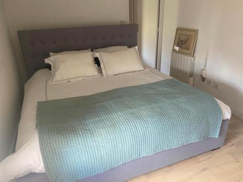 a large bed with a green blanket on it at Appartement les sablas in Saint-Tropez