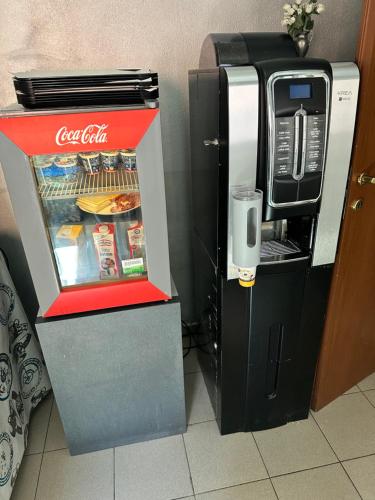 una nevera de cocacola junto a una máquina de coca-cola en Hotel Mercurio, en Milán