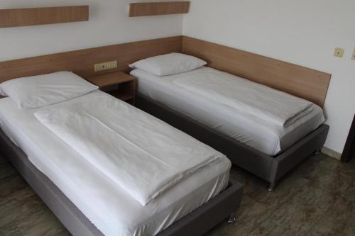 two twin beds in a room with a table at Apparthotel Alte Innbrücke-24Std-Self-Check in-Haustiere Willkommen in Neuhaus am Inn