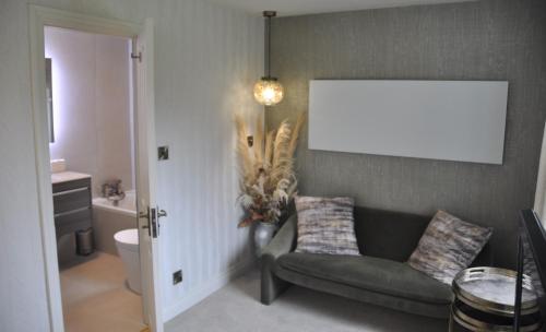 a living room with a couch and a bathroom at Tir y Coed Country House in Conwy