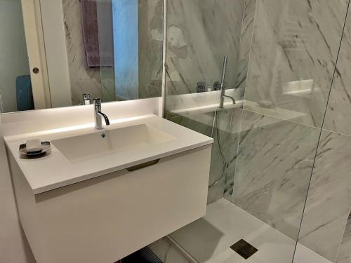 La salle de bains blanche est pourvue d'un lavabo et d'une douche. dans l'établissement Alva Luxury Flat, à Matosinhos