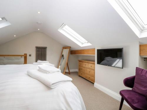 a bedroom with a bed and a tv on the wall at Jessamine Cottage in Ambleside