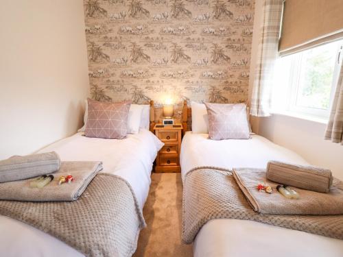 two twin beds in a room with wallpaper at Rose Dene in Brough