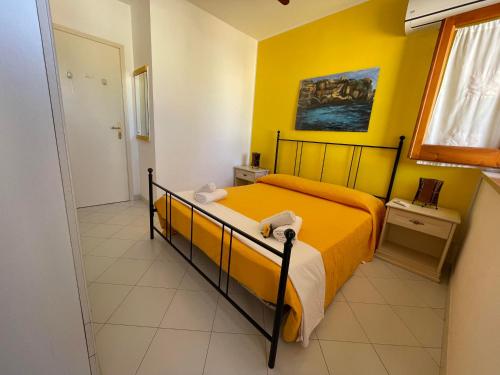 a bedroom with a bed and a yellow wall at Appartamento Girasole in San Vito lo Capo