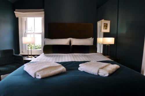 a bedroom with a bed with two towels on it at Tir y Coed Country House in Conwy
