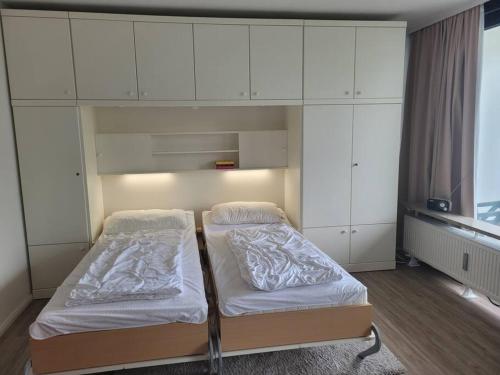 two beds in a room with white cabinets at Scharbeutz, 1 Raum Fewo mit sonnigem Balkon, ruhig und zentral in Scharbeutz