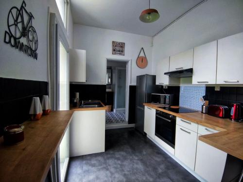 een keuken met witte kasten en een zwarte koelkast bij Le Loge'Mans Appartement proche gare , Tram et centre ville in Le Mans