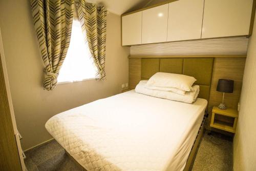 een slaapkamer met een groot wit bed en een raam bij Luxury Caravan With Decking Nearby Scratby Beach In Norfolk Ref 50001bm in Great Yarmouth