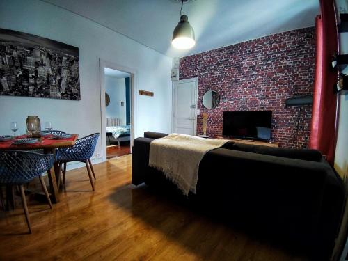 a bedroom with a brick wall and a bed and a table at Le Loge'Mans Appartement proche gare , Tram et centre ville in Le Mans