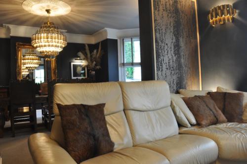 a living room with a white couch and a chandelier at Tir y Coed Country House in Conwy