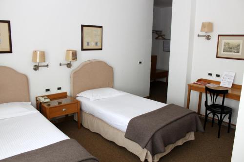 a hotel room with two beds and a desk at Hotel Miramonti in Schio