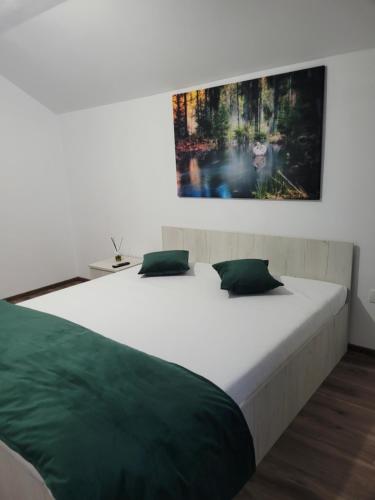 - une chambre avec un grand lit blanc et des oreillers verts dans l'établissement Colt de Rai, à Berislăveşti