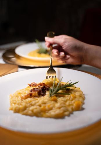 a person eating a plate of food with a fork at Relais Forte Benedek Wine & SPA - Adults Only in Pastrengo