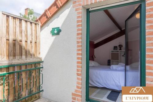 a sliding glass door leading to a bedroom with a bed at L'Atypique T3 Stanislas Maisonnette avec cour in Orléans