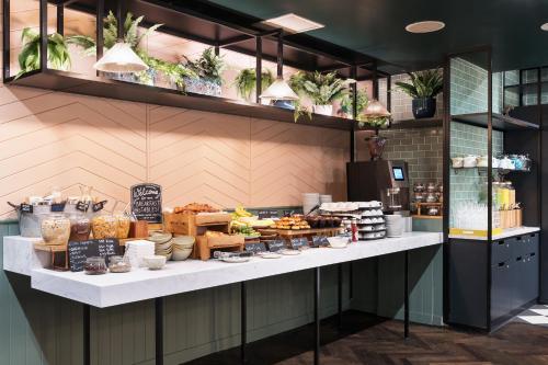 a bakery counter with a lot of food on display at Hotel Indigo London - Kensington by IHG in London