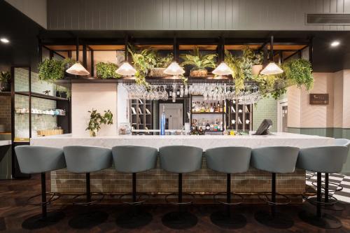 a bar with a white counter and some chairs at Hotel Indigo London - Kensington by IHG in London