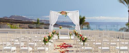a wedding ceremony with white chairs and a altar at H10 Atlantic Sunset Horizons Collection in Adeje