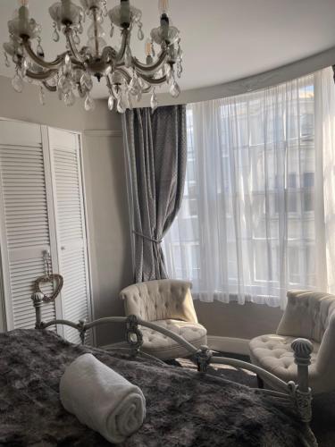 a bedroom with a bed and two chairs and a chandelier at Beautiful Seaview 2 Bedroom Apartment in Brighton & Hove