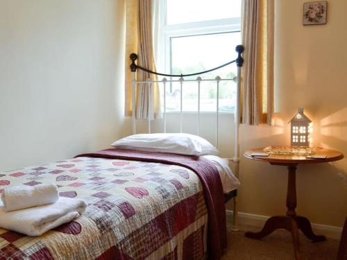 a bedroom with a bed with a table and a window at Bellringers Cottage, Llandegla in Llandegla