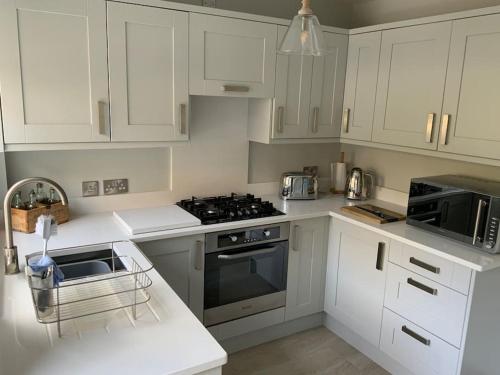 een keuken met witte kasten en een fornuis met oven bij A beautiful 1 bedroom home. in Matlock