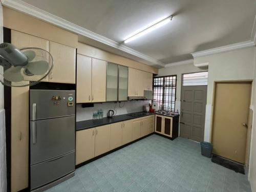 a large kitchen with white cabinets and a refrigerator at MY HOMESTAY BAHAU in Bahau