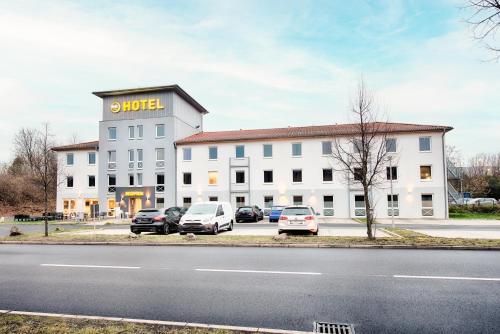 un grand bâtiment blanc avec des voitures garées devant lui dans l'établissement B&B Hotel Kassel-Süd, à Cassel