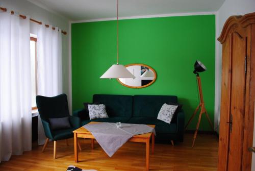 a green living room with a couch and a table at Landhaus Steinbrech in Grainau