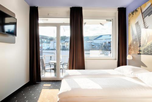 a bedroom with a bed and a large window at B&B Hotel Kiel-Holstenbrücke in Kiel