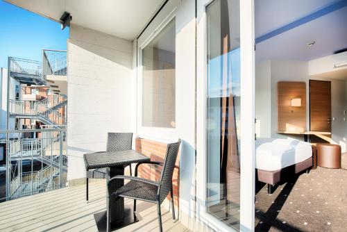 einen Balkon mit einem Tisch, Stühlen und einem Bett in der Unterkunft B&B Hotel Kiel-Holstenbrücke in Kiel