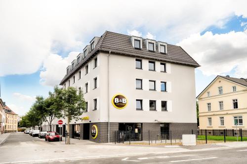 ein weißes Gebäude mit schwarzem Dach auf einer Straße in der Unterkunft B&B Hotel Gießen in Gießen