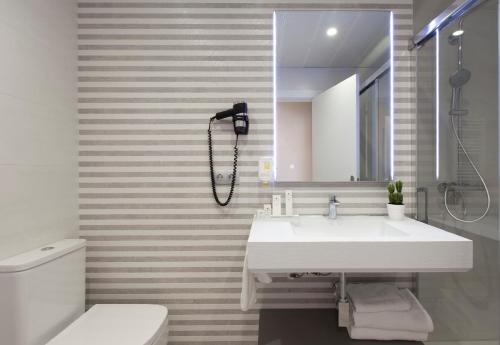 a bathroom with a sink and a mirror and a toilet at Spirit Hotel Ciudad de Burgos in Rubena