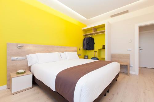 a bedroom with a large bed with a yellow wall at Spirit Hotel Ciudad de Burgos in Rubena