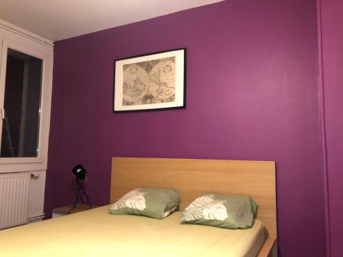 a bedroom with a purple wall and a bed with two pillows at Chambre meublée prune boulevard Joseph Vallier in Grenoble