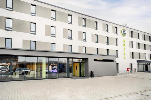 a large white building with a parking lot at B&B Hotel Kehl in Kehl am Rhein