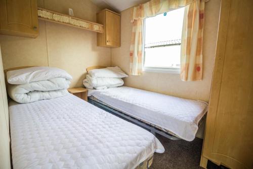 two beds in a small room with a window at 8 Berth Spacious Dog Friendly Caravan, Near Great Yarmouth In Norfolk Ref 10004g in Belton